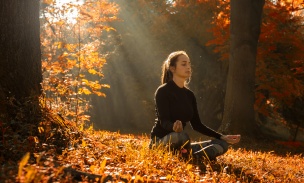 A young woman make yoga position at sunrise. in the autumn forest